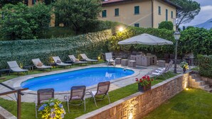 A swimming pool with lounge chairs and a table, surrounded by a stone wall and greenery. - Live the high life in Lake Como in a period villa with lake view & private pool (Menaggio)