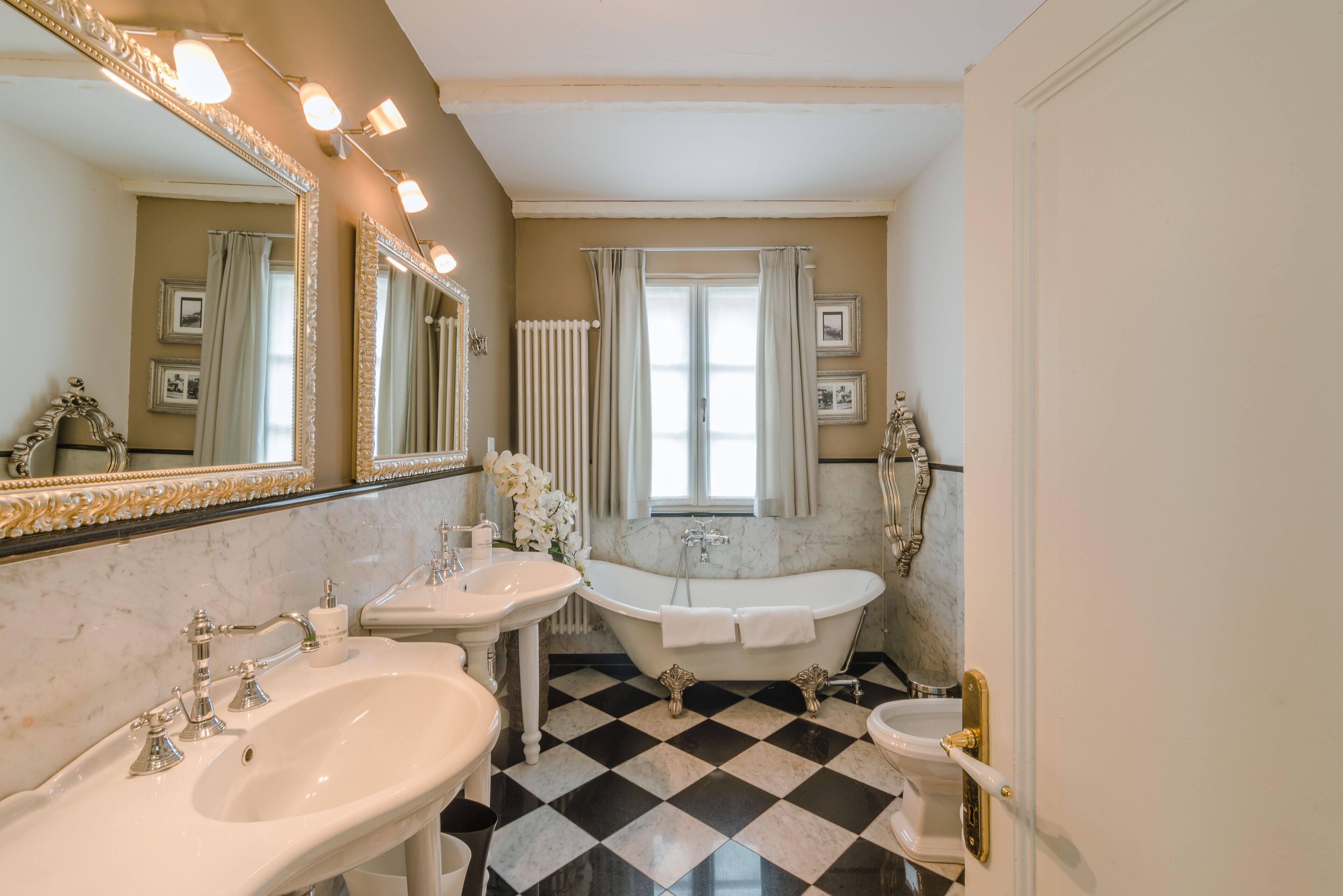 Une salle de bain avec deux lavabos, une baignoire et un grand miroir.