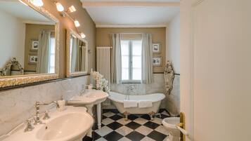 Une salle de bain avec deux lavabos, une baignoire et un grand miroir.