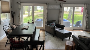 A spacious living area with a dining table, chairs, a sofa, and a large sliding glass door leading to a backyard. - 3 bedroom, 2 Baths, 8 Sleeps, detached bunk house, open boat slip (Ossipee, NH 03814)