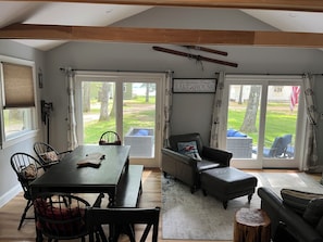 A spacious living area with a dining table, chairs, a sofa, and a large sliding glass door leading to a backyard. - 3 bedroom, 2 Baths, 8 Sleeps, detached bunk house, open boat slip (Ossipee, NH 03814)