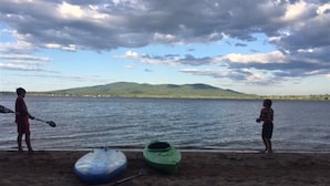 Two kayaks on a sandy beach with a body of water and distant hills. - 3 bedroom, 2 Baths, 8 Sleeps, detached bunk house, open boat slip (Ossipee, NH 03814)