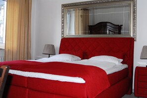 A bed with a red quilted headboard, white bedding, and a large mirror above it. - Wasserturm Hotel (Mannheim)