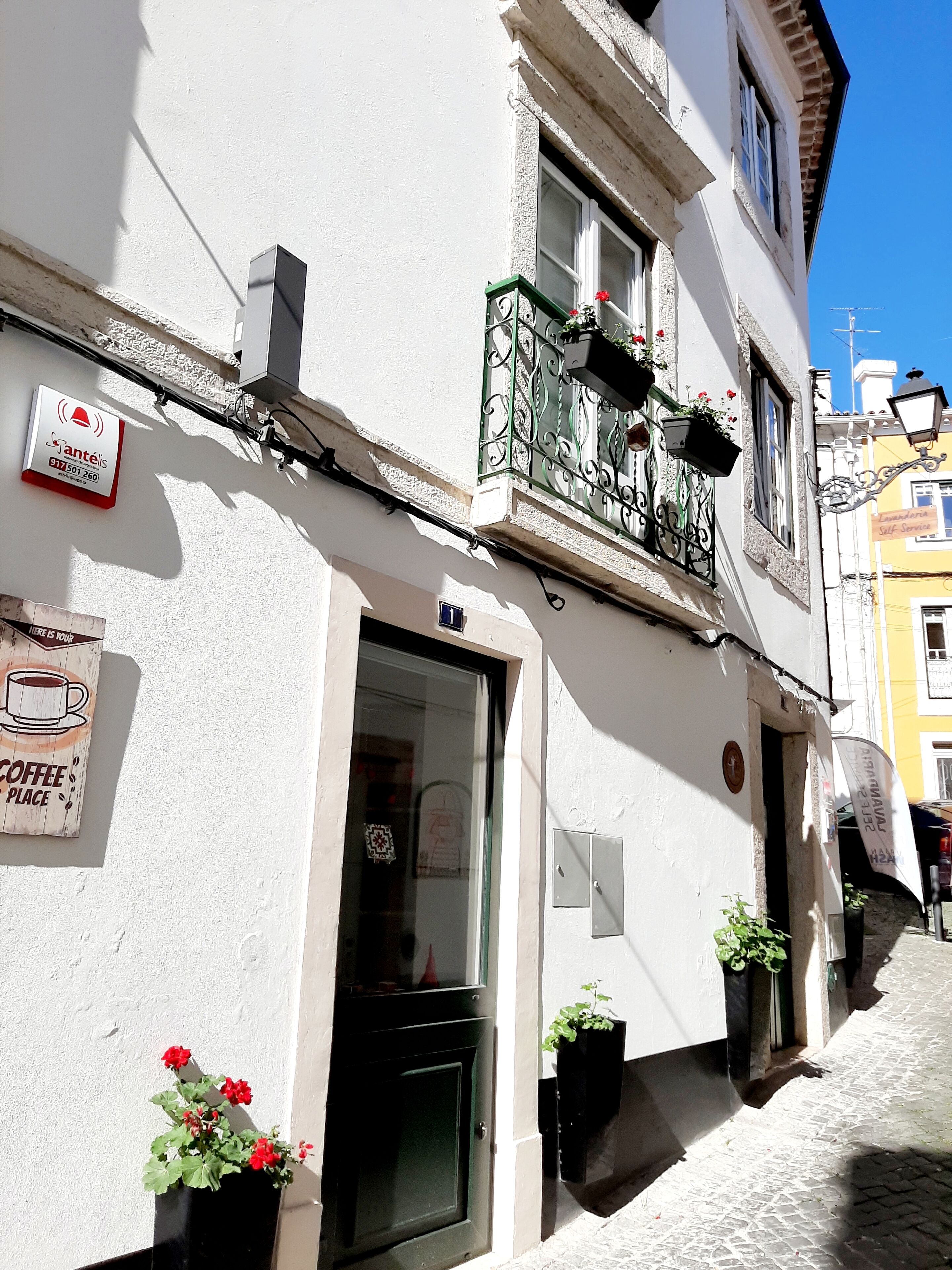 Ein Gebäude mit sichtbarer Schaufensterfront, einer Tür und einem Balkon mit Fenster.