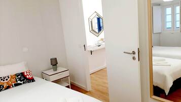 Une chambre d’hôtel comprenant un lit, une table de chevet, une lampe, un miroir et une porte donnant sur une autre pièce.