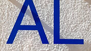 A large blue 'AL' sign with the text 'Alojamento Local' below it, set against a textured white background.