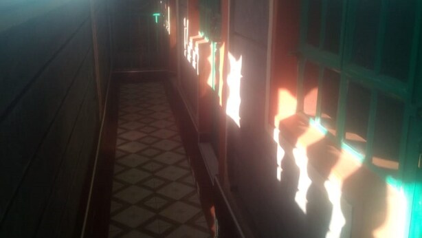 A narrow hallway with patterned floor tiles, wooden walls, and illuminated windows. - Tripple Arrow Guest House (Nairobi)