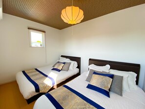 Une chambre d’hôtel avec deux lits, une fenêtre et un luminaire suspendu.