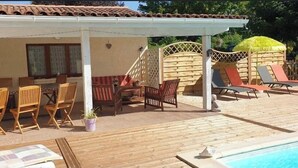 Un espacio exterior cubierto con piscina, muebles de madera y una estructura de techo de paja.