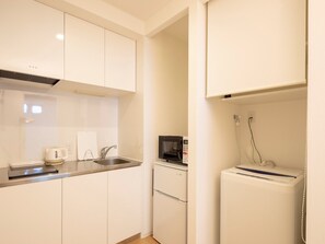 Efficiently designed kitchen with white cabinetry, stainless steel countertop, and essential appliances.