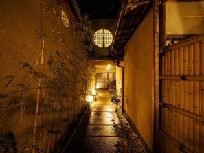 A narrow alleyway with traditional Japanese architecture, including a wooden gate and a circular window. - Ks Villa KamogawaanA Kyomachiya Rental House wi / Kyoto Kyōto (Kyoto)