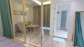 A hotel room with a bed, a seating area with cushions, a wooden partition, and a bathroom door. - Bohol Sojourn (Panglao)