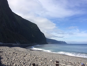 A rocky beach with a steep cliff on one side and a calm sea. - APARTAMENTO FÉRIAS FELIZES (Funchal)