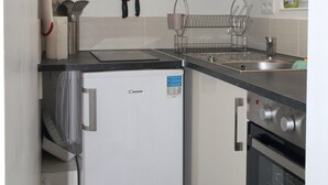 A compact kitchen with a refrigerator, stove, and sink. - Independent studio in a quiet building with small patio (Vernet-les-Bains)