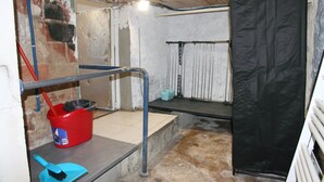 A basement with a red bucket, a blue broom, and a black plastic cover on the wall. - Independent studio in a quiet building with small patio (Vernet-les-Bains)
