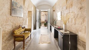 A hallway with a bench, a rug, and a desk with a vase. - Appartamento Ai Fiorentini by BarbarHouse (Lecce)