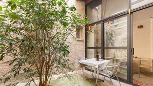 A patio area with a table and chairs, a potted plant, and a sliding glass door leading to an interior space. - Appartamento Ai Fiorentini by BarbarHouse (Lecce)