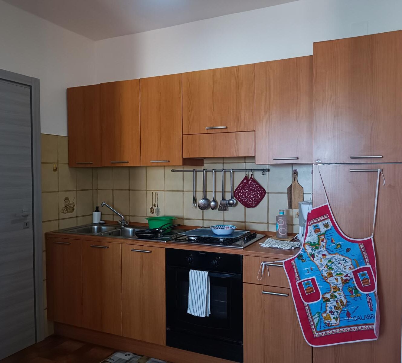 A kitchen with wooden cabinets, a stove, a sink, and a hanging pot rack.