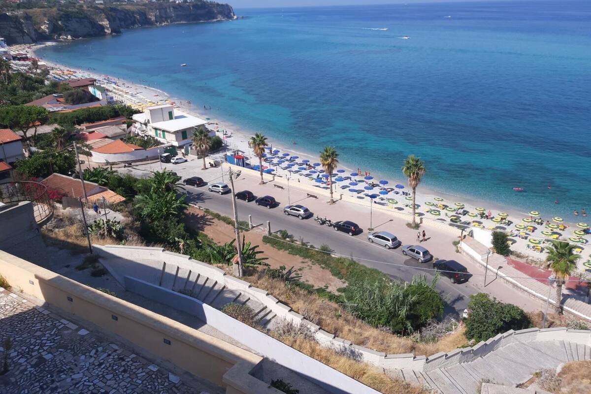 Una carretera costera con aparcamiento en la playa y sombrillas.