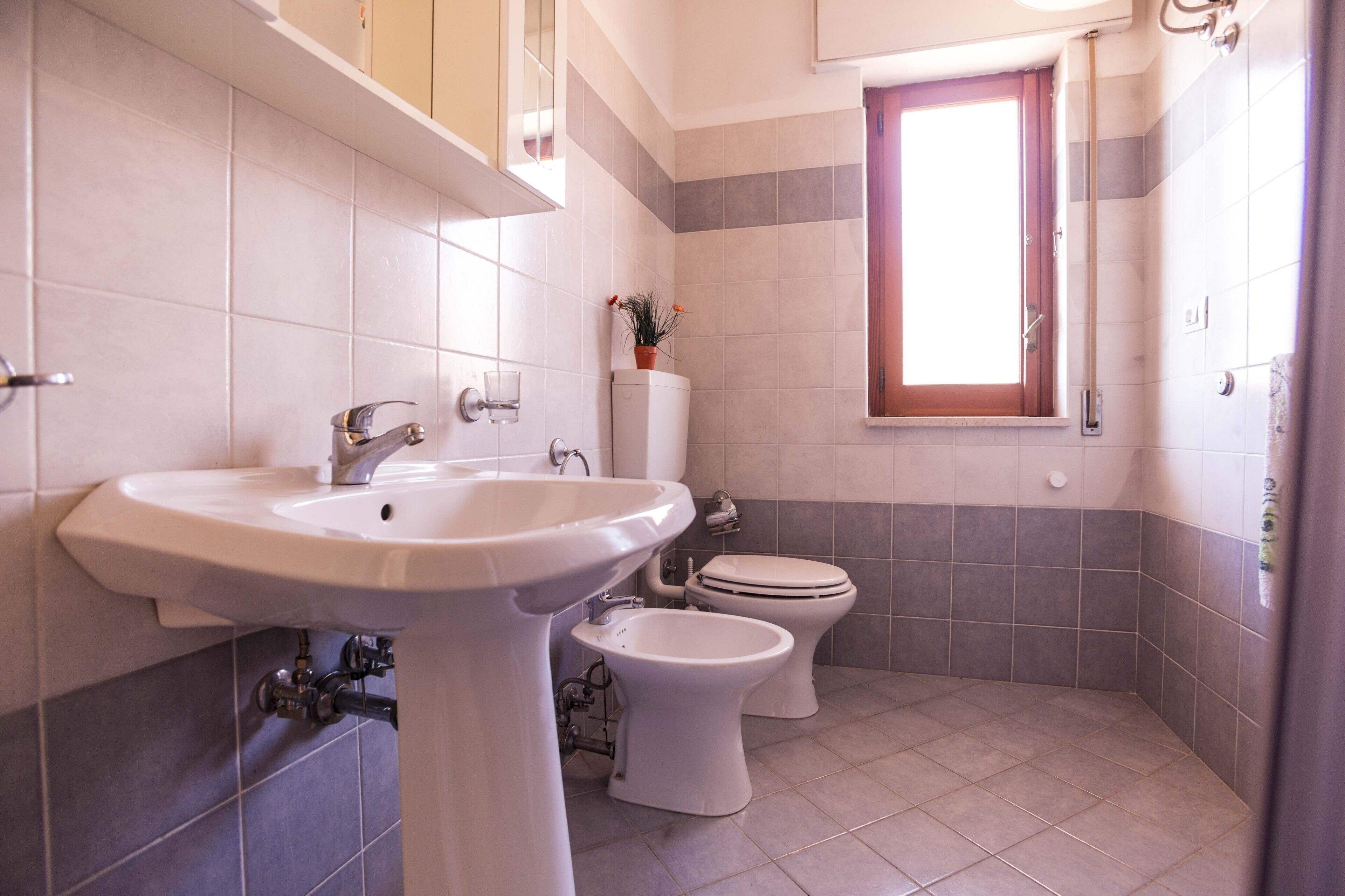 Un baño con lavabo, inodoro y ventana.