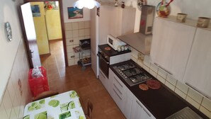A kitchen with a stove, microwave, and cabinets. There is a red basket and a table with a lime-patterned tablecloth. - Sabbia (Tropea)
