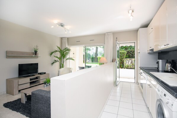 A modern apartment with a living area, kitchen, and balcony.