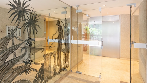 A modern reception area with a glass partition, a reception desk, and a view of the lobby.