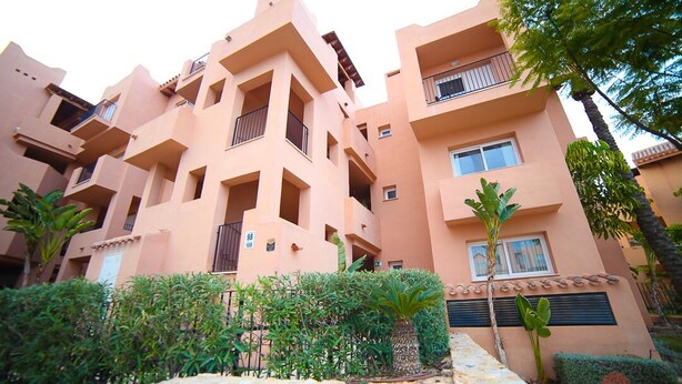 A multi-story building with balconies and a stone wall in the foreground. - Apartment - Sleeps 4 - Pool - Terrace - Parking (Torre-Pacheco)