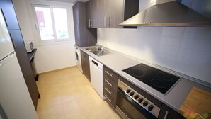 A modern kitchen with a built-in oven, stovetop, and dishwasher. - Apartment - Sleeps 4 - Pool - Terrace - Parking (Torre-Pacheco)
