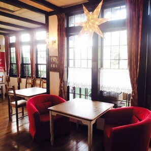 Traditional interior with two tables, chairs, and framed pictures, featuring a star-shaped light fixture and large windows.