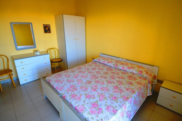 A bedroom with a bed, a dresser, a wardrobe, a chair, and a mirror.