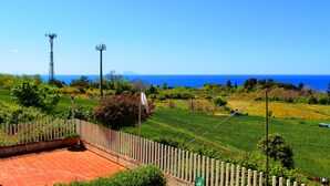 A view of a rural landscape with a clear blue sky, a wooden fence, and a satellite dish. - Casa Vacanze del Sole (Ricadi)