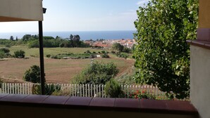 A balcony with a view of a coastal town, greenery, and a clear sky. - Casa Vacanze del Sole (Ricadi)
