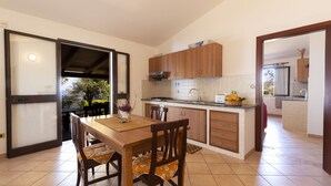 Una cocina moderna con armarios de madera, una mesa de comedor con sillas y vistas a través de un puerta abierta.