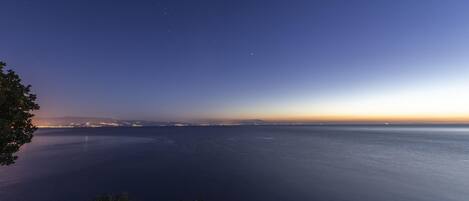 A coastal view at dusk with a silhouette of a person on a cliff overlooking the sea.