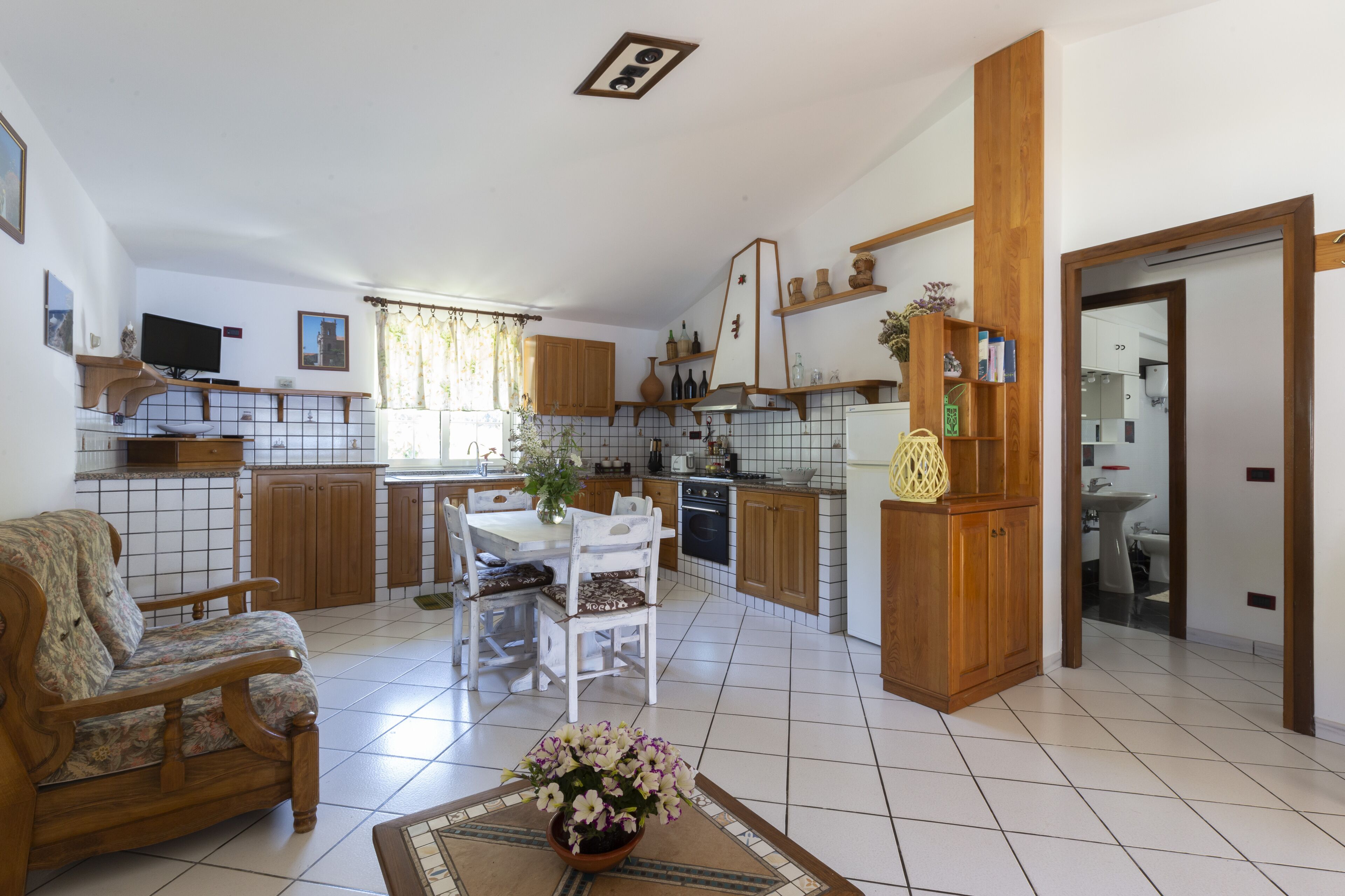 A spacious living area with a sofa, a dining table, and a kitchen in the background.