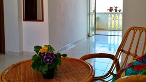 A room with a round wicker table, two wicker chairs, a potted plant, and a book. - Villa Cecile (Ricadi)
