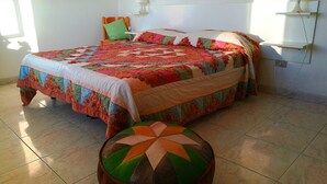 A neatly arranged bedroom with a large bed, a bedside table, a lamp, and a decorative stool. - Villa Cecile (Ricadi)
