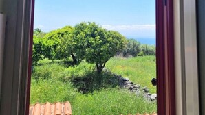Puerta que da a un balcón con vista a un árbol y un paisaje distante.