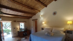 Un dormitorio con cama, mesitas de noche, cómoda, ventana y puerta que da a un espacio exterior.