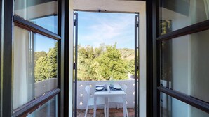 An open balcony with a table set for two, overlooking a lush green landscape.