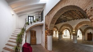 A spacious interior with a staircase, arched ceilings, and a red chair.