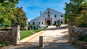 Un bâtiment blanc avec une entrée en pierre, une allée pavée et une pelouse bien entretenue.