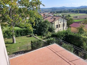 Une terrasse offrant une vue sur un paysage rural, avec des maisons et des champs.
