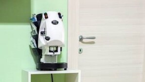 Una habitación con una puerta blanca, un estante blanco con una cesta y una máquina de café.