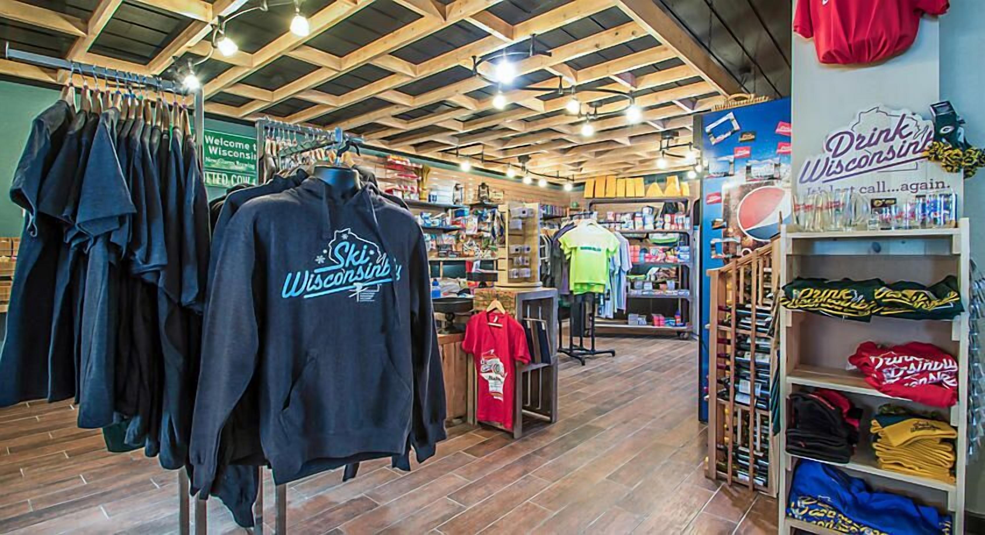 Una tienda con vigas de madera en el techo, estantes con diversos artículos, y un letrero que dice "Drink Wisconsin".