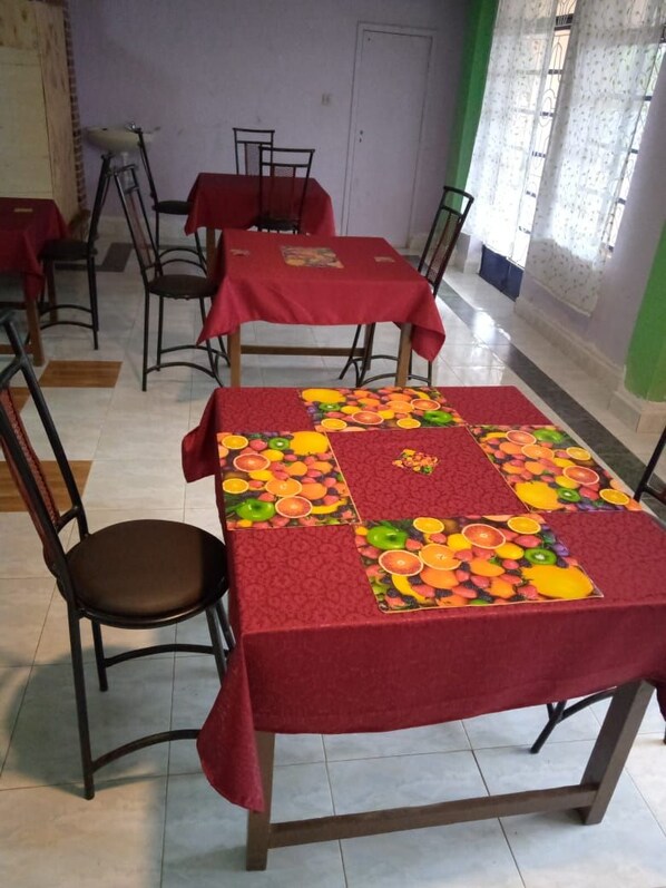 A dining area with tables covered in red tablecloths and chairs.