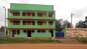 A multi-story building with balconies, a dirt road in front, and a sign for the Besson Hotel Bungo. - Beston Hotel Bungoma (Chwele)