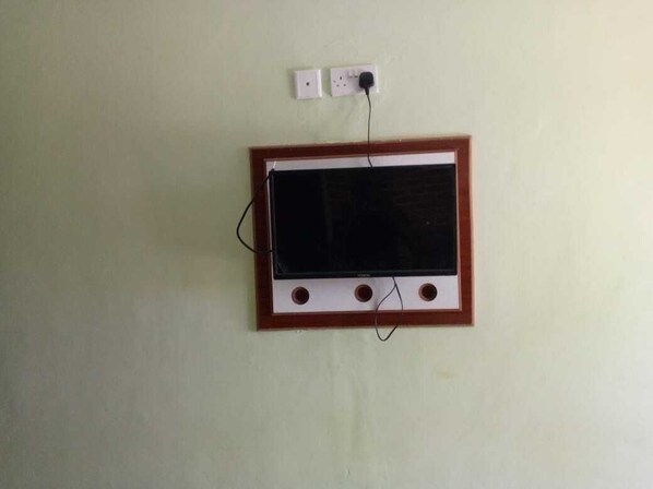 A television mounted on a wall with a power outlet above it. - Beston Hotel Bungoma (Chwele)