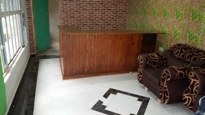 A room with a wooden reception desk, a patterned sofa, and a tiled floor with a geometric design. - Beston Hotel Bungoma (Chwele)